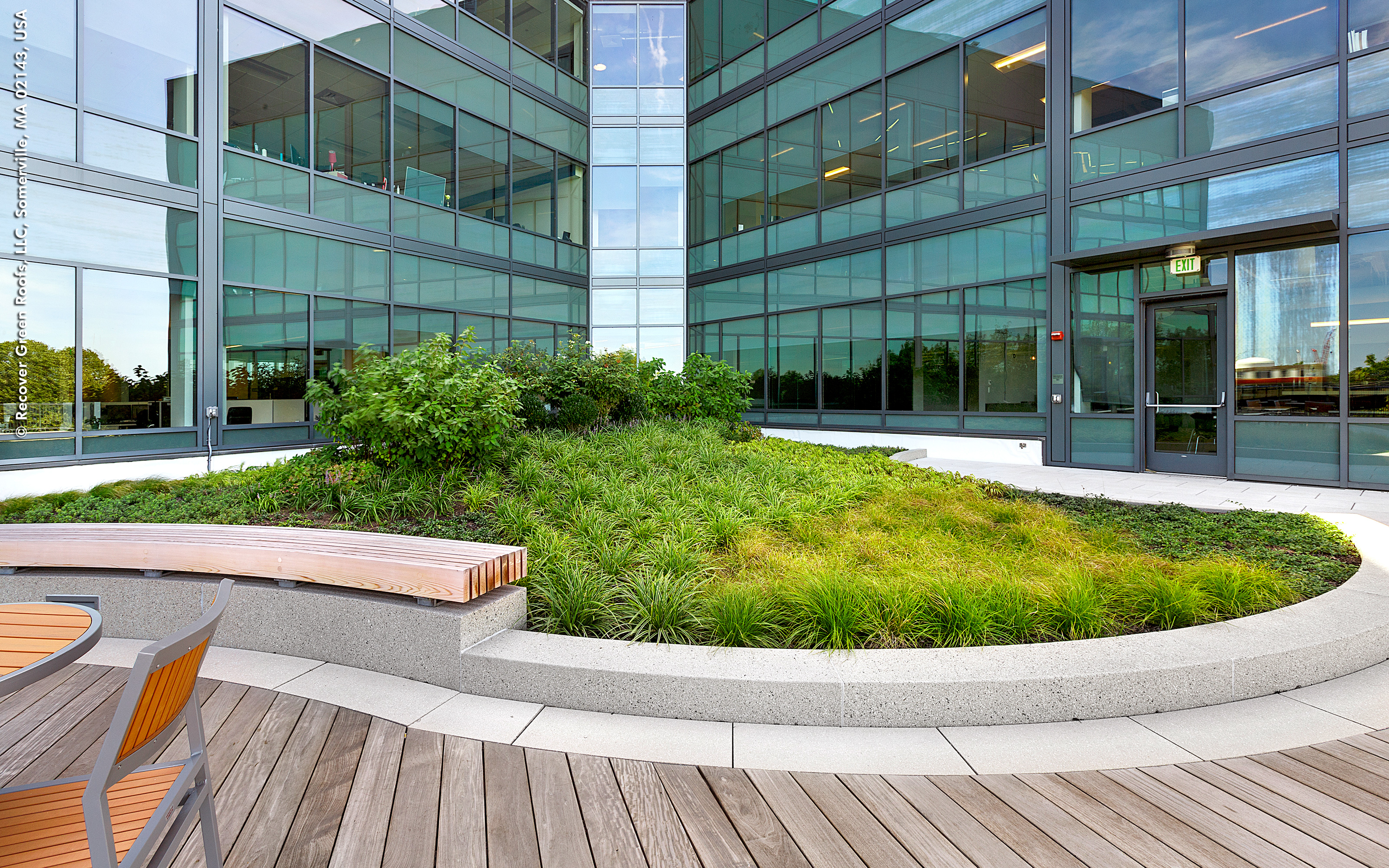 Seating areas create natural gathering spaces on the roof. Roof terrace with walkways and a curved bench